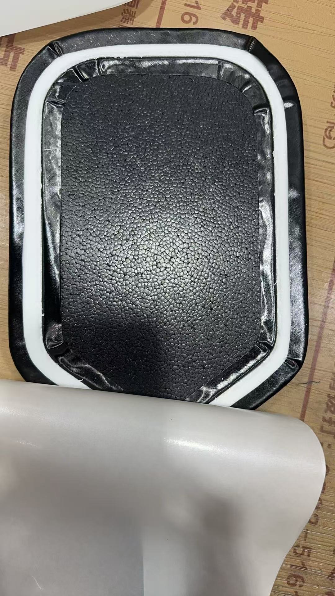 Close-up of thermoformed paddle construction - a textured raw-carbon face over the honeycomb core with a white EPP foam perimeter around the edge
